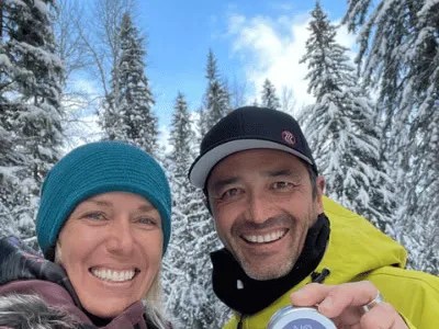 Melanie and Chris, the founders, smiling in a snowy forest, Chris holding up a No Pong tin